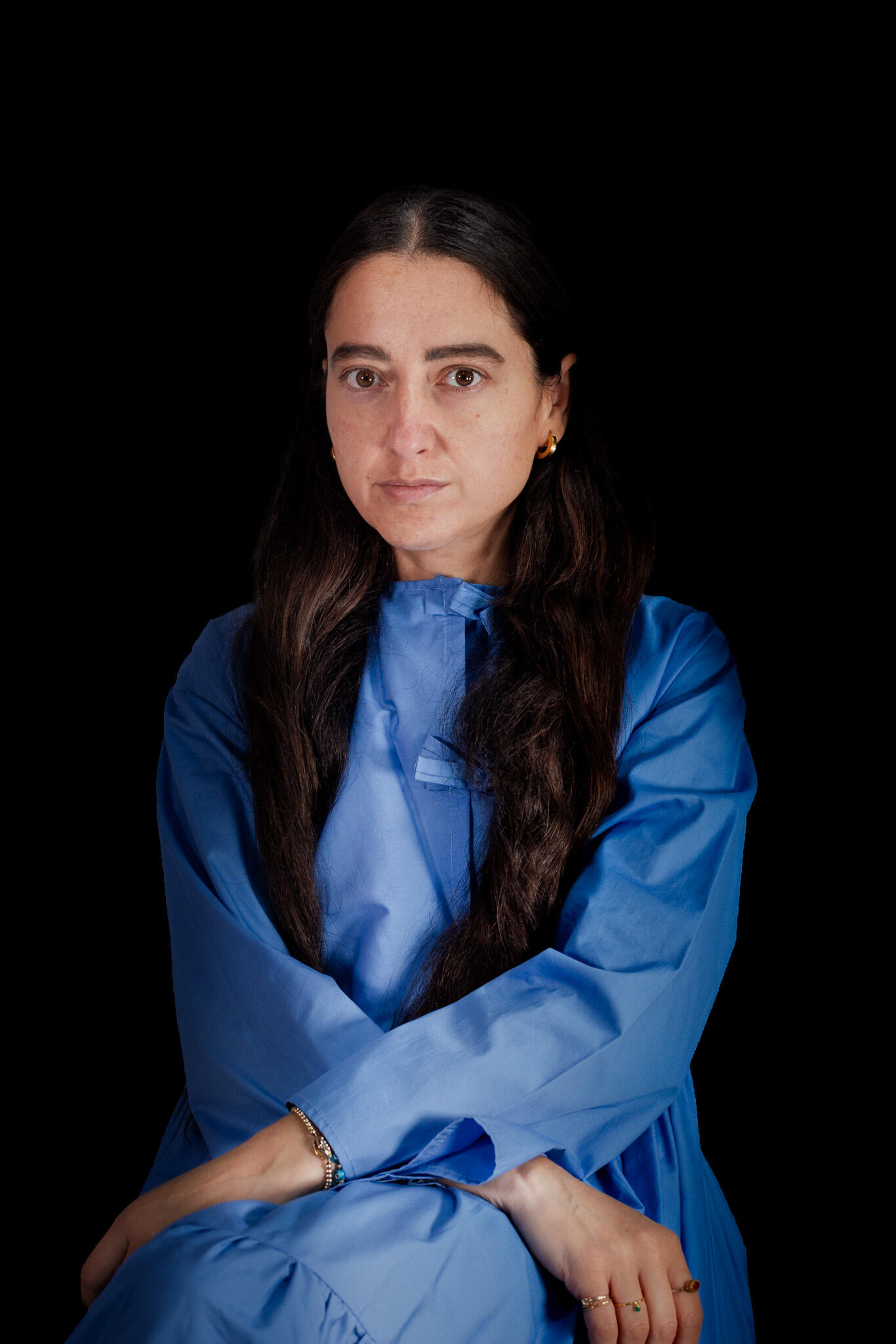 Alina Stanila | Fashion Designer Portrait Portrait of Alina Stanila, founder and creative director of Mystic Moods, seated in a blue dress against a black studio background.